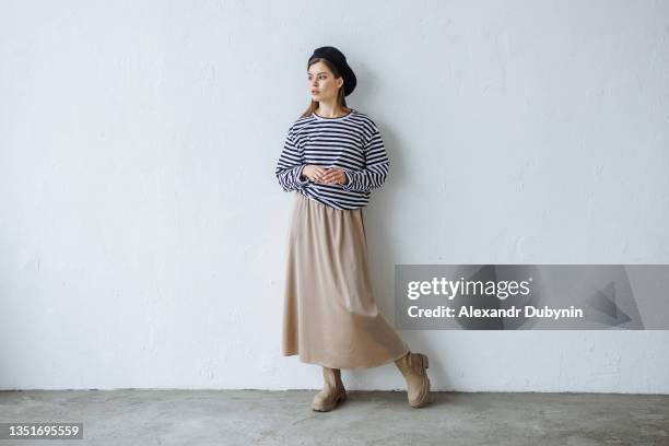 stylish model posing in the studio against a white wall in a new collection of clothes - falda fotografías e imágenes de stock