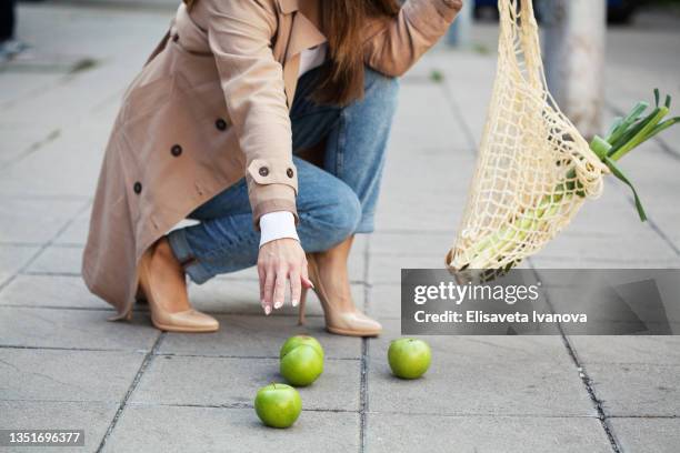 young woman dropping groceries on sidewalk - lower stockfoto's en -beelden