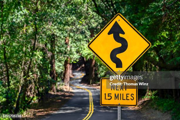 winding road warning sign in a forest - curve road sign stock pictures, royalty-free photos & images