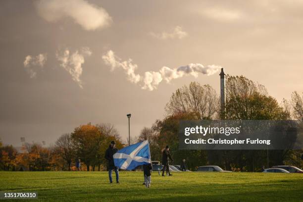 Child runs with a saltire flag as steam emits from a chimney at Glasgow Green as climate protestors gather for the Global Day of Action for Climate...