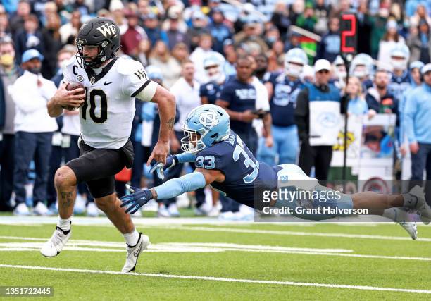Sam Hartman of the Wake Forest Demon Deacons breaks away from Cedric Gray of the North Carolina Tar Heels for a touchdown during the second half of...