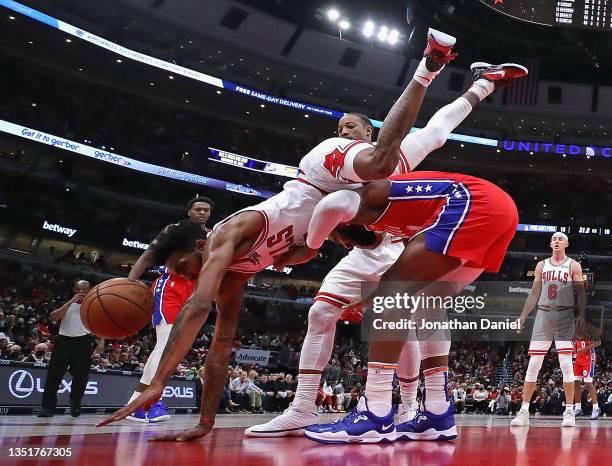 Derrick Jones Jr. #5 of the Chicago Bulls falls over Andre Drummond of the Philadelphia 76ers after knocking the ball away from Drummond at the...