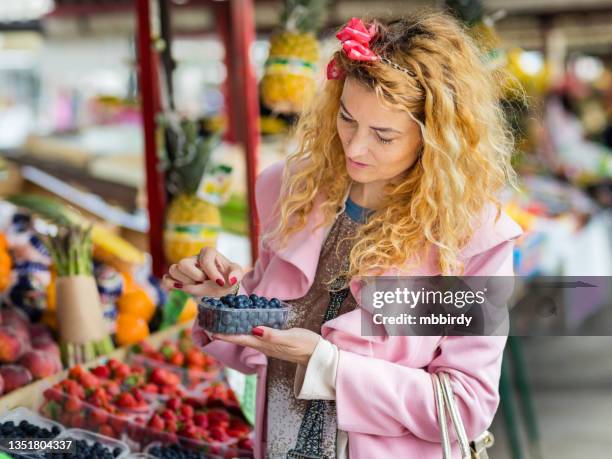 nette frau, die blaubeeren auf dem marktplatz in der stadt kauft - laibach stock-fotos und bilder