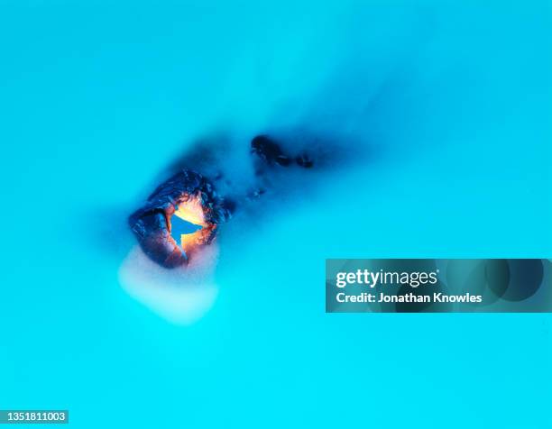 hole burning in blue paper - burning stock pictures, royalty-free photos & images