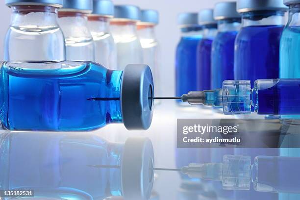 laboratory bottles with blue content and a syringe - infectious disease no people stock pictures, royalty-free photos & images