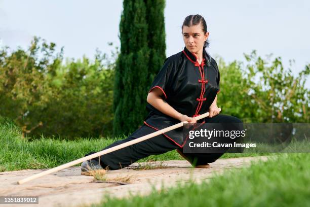 woman in uniform practicing martial arts with a stick - kung fu fotografías e imágenes de stock