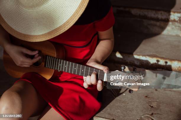 top view of sitting girl playing ukulele, close-up - sommerkleid stock-fotos und bilder