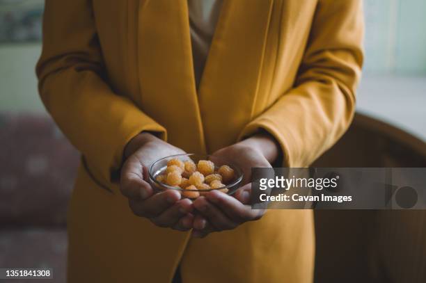 yellow raspberries in glass plate in hands - frock coat 個照片及圖片檔