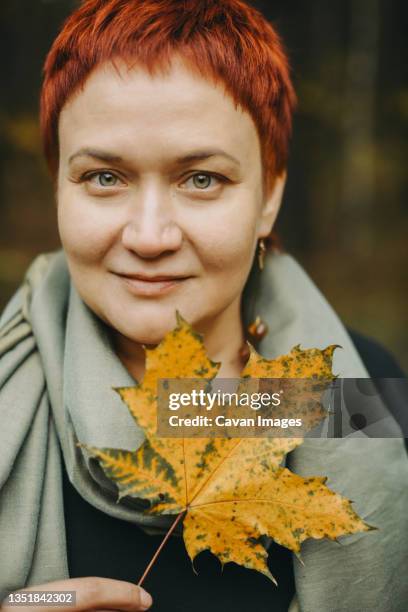 middle-aged woman of 30-40 years old with autumn maple leaf - woman 30 years old portrait stock pictures, royalty-free photos & images