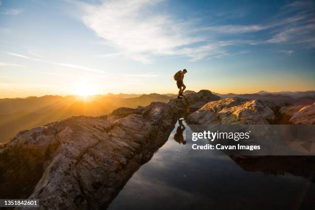 backpacker hiking over rocky mountain terrain at sunset. - vancouver stock pictures, royalty-free photos & images