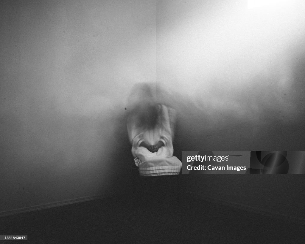 Scary ghost girl sitting in foggy haunted corner of house