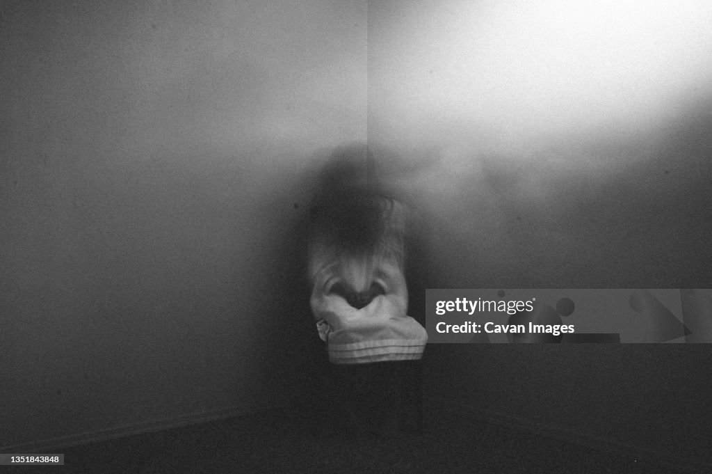 Ghost girl sitting in dark foggy corner of haunted house
