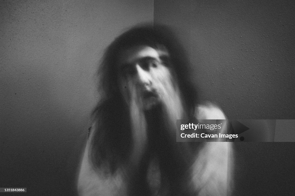 Portrait of spooky girl against wall at home