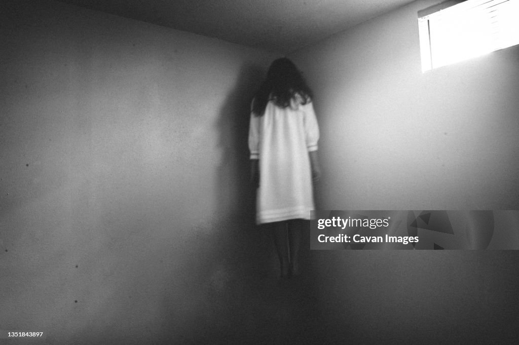 Scary girl in nightgown hovering in the corner of room