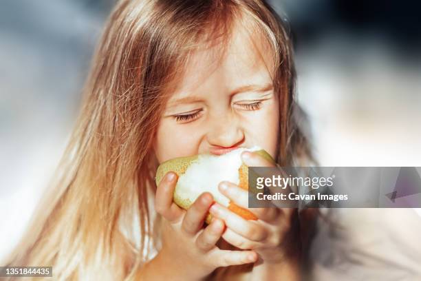 girl in the morning eating a pear in bed - chil morning stock pictures, royalty-free photos & images