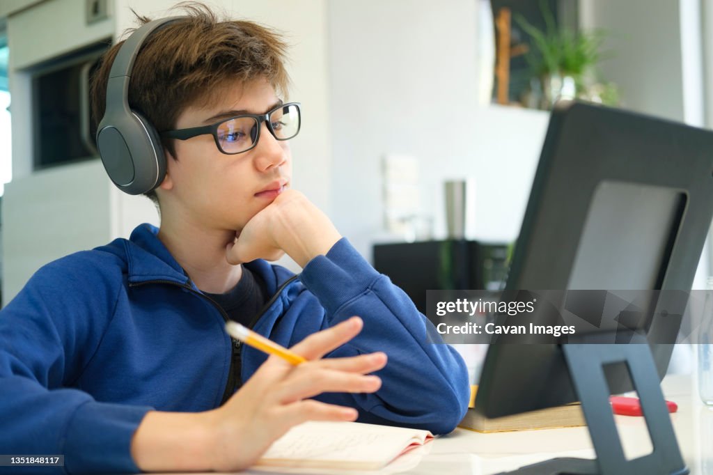 Student boy with tablet computer learning at home