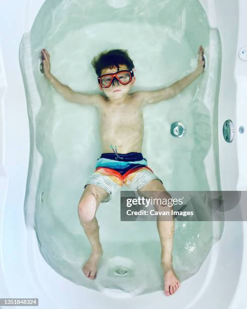 moody boy in a large bathtub wearing swim trunks and a diving mask - arlington virginia ストックフォトと画像