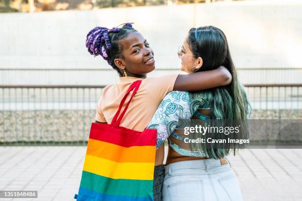 content multiethnic lesbian girlfriends embracing on walkway - lesbian dating 個照片及圖片檔