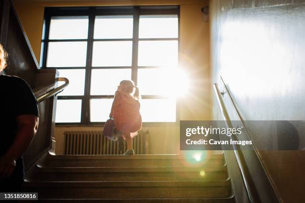 girl going to first day of school walking up stairs - erster schultag stock-fotos und bilder