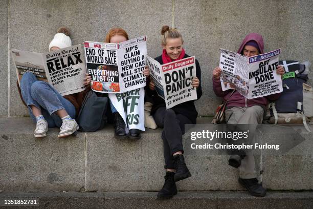 Climate change activists read mock newspapers in George Square, Glasgow in support of victims of oil exploration and against fossil fuel investments...