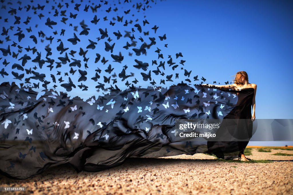Mysterious woman releasing butterflies in desert