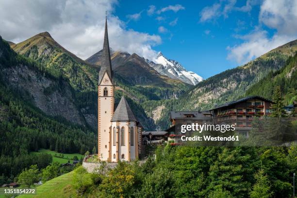 austria, carinthia, heiligenblut am grossglockner, mountain village withsaint vincent church in center - grossglockner stock-fotos und bilder