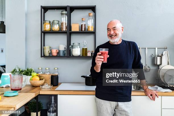 happy man holding smoothie glass in kitchen - blended drink ストックフォトと画像