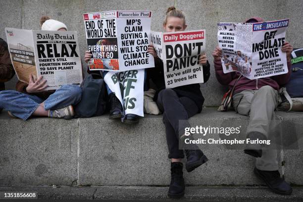 Climate change activists read mock newspapers in George Square, Glasgow in support of victims of oil exploration and against fossil fuel investments...