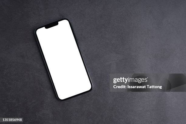 mobile phone with empty screen on black desktop. top view - oberteil stock-fotos und bilder