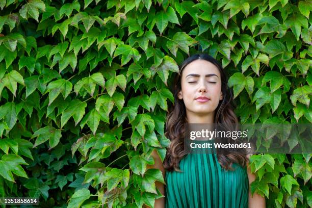 beautiful young woman with eyes closed leaning on ivy leaves - hair growth stock pictures, royalty-free photos & images