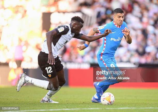 Luis Suarez of Atletico Madrid battles for possession with Mouctar Diakhaby of Valencia CF during the La Liga Santander match between Valencia CF and...