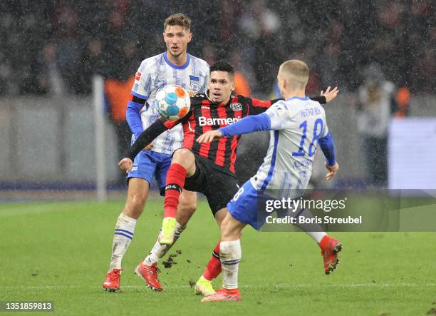 Paulinho of Bayer 04 Leverkusen is challenged by Niklas Stark and Santiago Ascacibar of Hertha Berlin during the Bundesliga match between Hertha BSC...