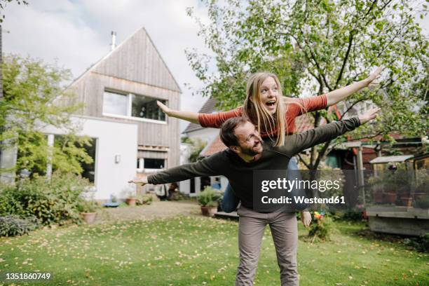 cheering couple pretending to fly, standing in their garden - hacer el avión fotografías e imágenes de stock