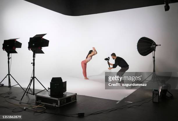 woman practicing yoga, while professional photographer shooting in photo studio - backstage photography stock pictures, royalty-free photos & images