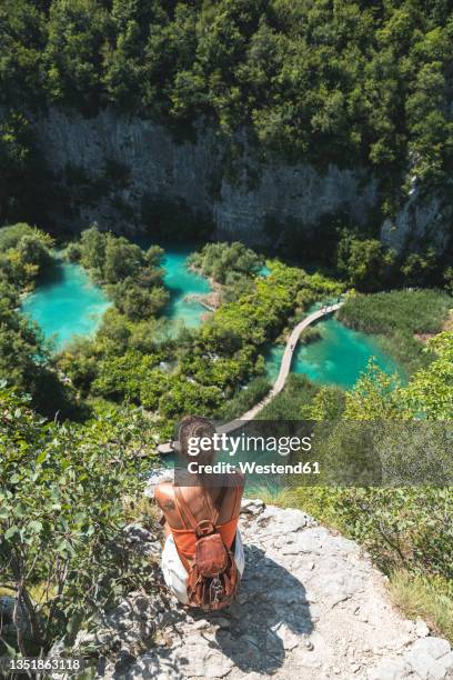 female hiker admiring landscape of plitvice lakes national park from edge of cliff - plitvice lakes national park stock pictures, royalty-free photos & images