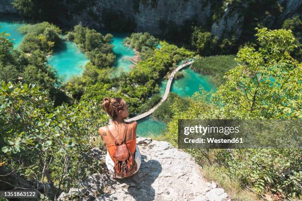 female hiker admiring landscape ofplitvicelakes national park from edge of cliff - plitvice lakes national park stock pictures, royalty-free photos & images