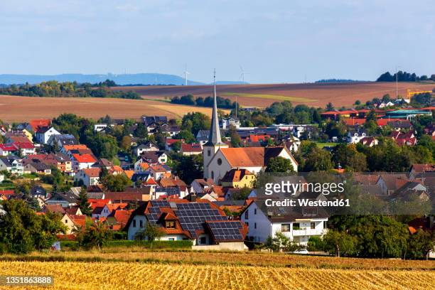 rural village in autumn with church and solar panel equipped house in center - village stock-fotos und bilder