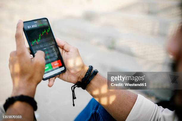man checking stock market graph through mobile phone - stock market graph stock-fotos und bilder