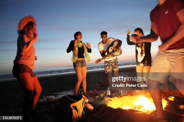 young people having party on beach - bonfire night uk stock-fotos und bilder