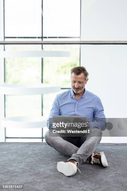 businessman using laptop while sitting on ground in corridor - sitting on ground stock pictures, royalty-free photos & images