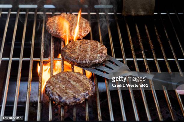 burgers cooking onbarbecue grill - spatola foto e immagini stock