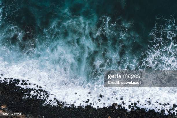 vista aérea de las olas del océano rompiendo en la playa rocosa - oceano fotografías e imágenes de stock