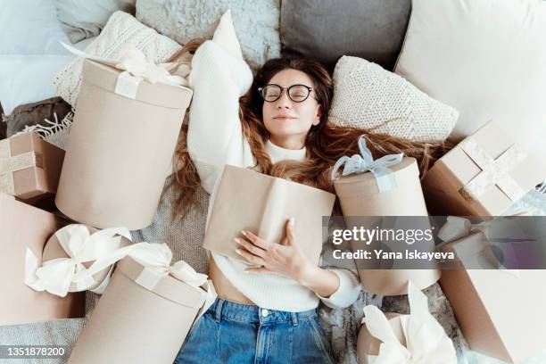 beautiful woman in glasses is reading a book, she is a bookworm enjoying the black friday sale offers - shopaholic woman stock pictures, royalty-free photos & images