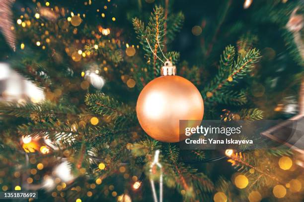 bright orange christmas ball hanging on a fir tree with glitters around - pracht tanne stock-fotos und bilder