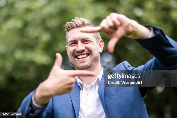 happy young businessman making finger frame - finger frame stock-fotos und bilder