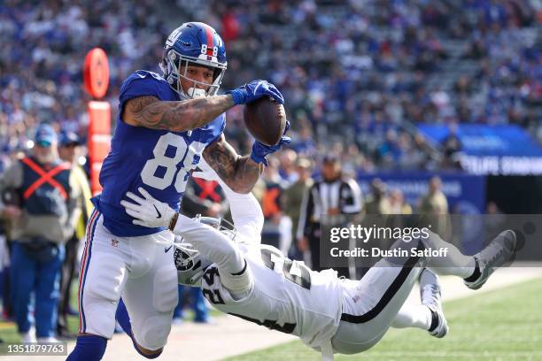 Evan Engram of the New York Giants scores a touchdown while defended by Johnathan Abram of the Las Vegas Raiders during the first quarter at MetLife...