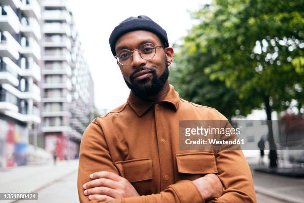 confident man with arms crossed in city - man with facial hair stock pictures, royalty-free photos & images