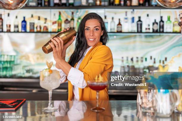 female bartender preparing cocktails in bar - cocktail shaker stock pictures, royalty-free photos & images