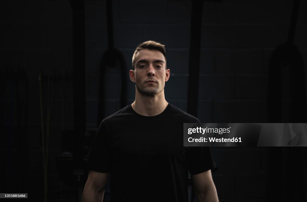 Confident male athlete in front of black wall