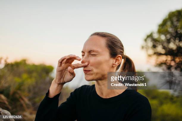 woman with eyes closed scratching nose - nose stock pictures, royalty-free photos & images